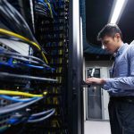 Young IT engineer inspecting data center servers.
